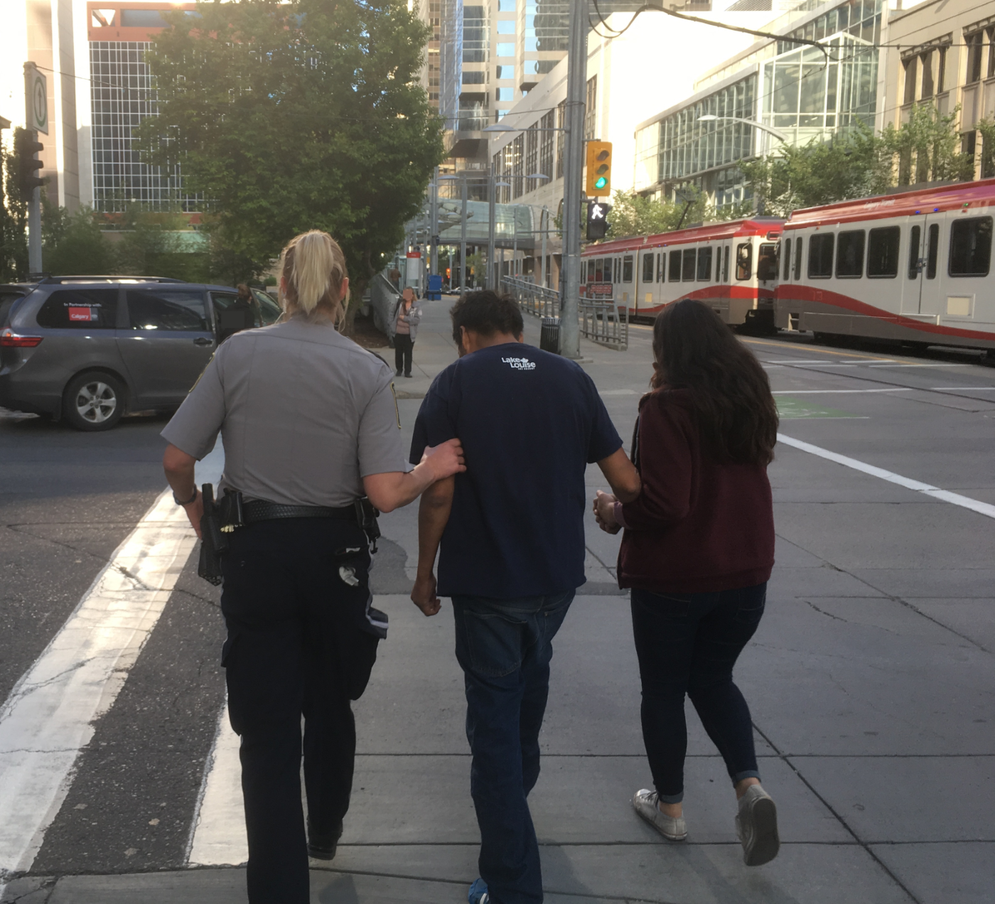 Photo of man being assisted by a Transit officer and an outreach worker. 